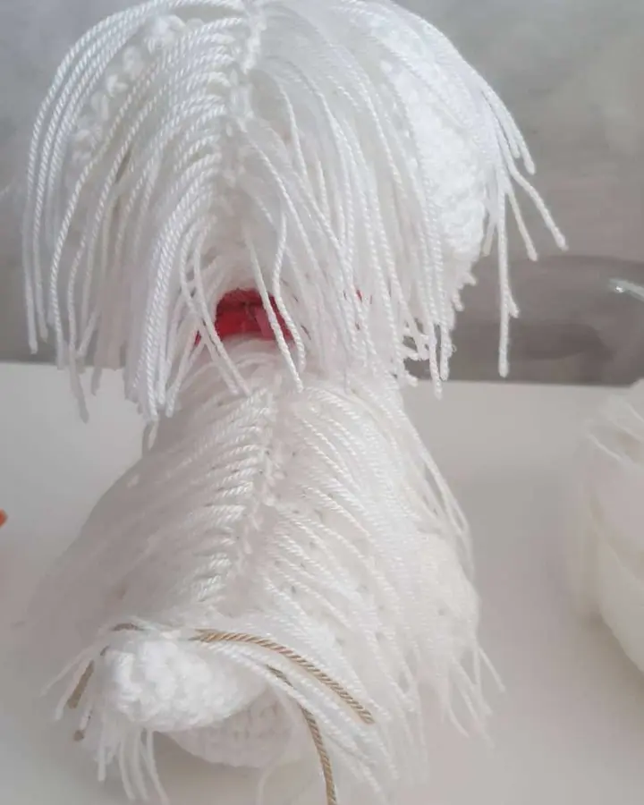 Amigurumi de bichón maltés blanco visto de lado, con el pelo largo tejido a mechones