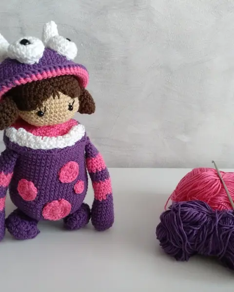 Amigurumi de una niña con dos coletas y camiseta rosa, tejido a crochet