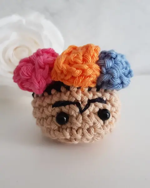 Broche de crochet con la cara de Frida Kahlo y una corona de flores de colores