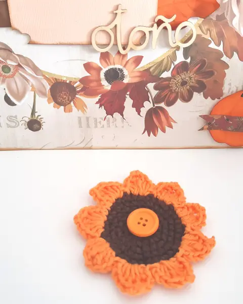 Broche de crochet con forma de girasol, pétalos amarillos y centro marrón, sobre fondo claro