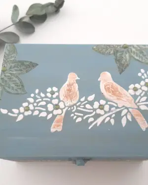 Caja de madera pintada en azul grisáceo con dos pájaros en decoupage sobre la tapa