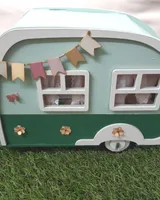 Caravana de madera vista por detrás, con la puerta pintada y las ruedas de madera