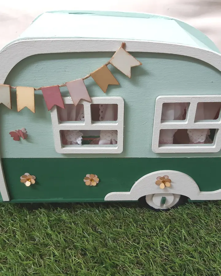 Caravana de madera vista por detrás, con la puerta pintada y las ruedas de madera