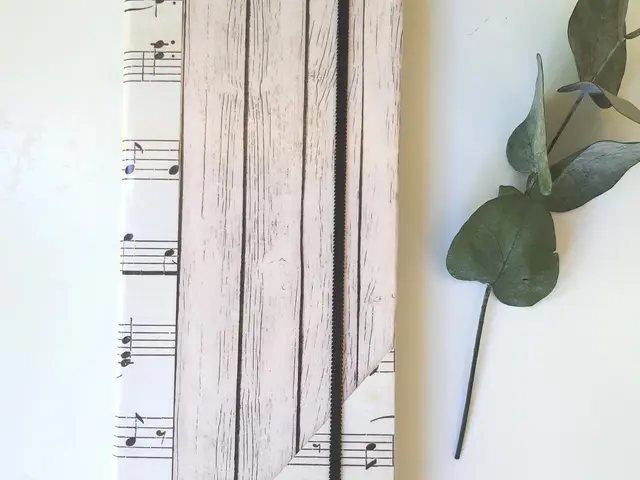 Porta tratados forrado con papel de partituras en tonos crema y sepia, con cierre de goma