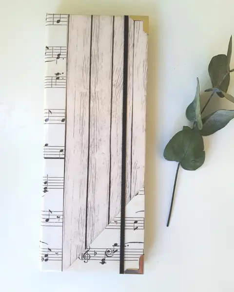 Porta tratados forrado con papel de partituras en tonos crema y sepia, con cierre de goma