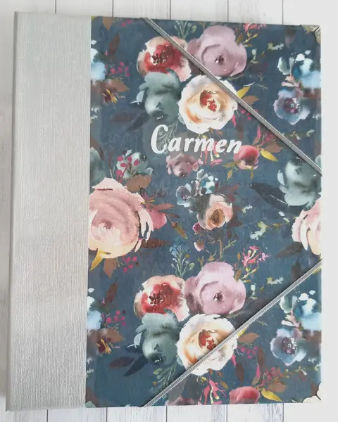 Carpeta para revistas forrada con papel de rosas sobre fondo gris, cerrada con goma elástica