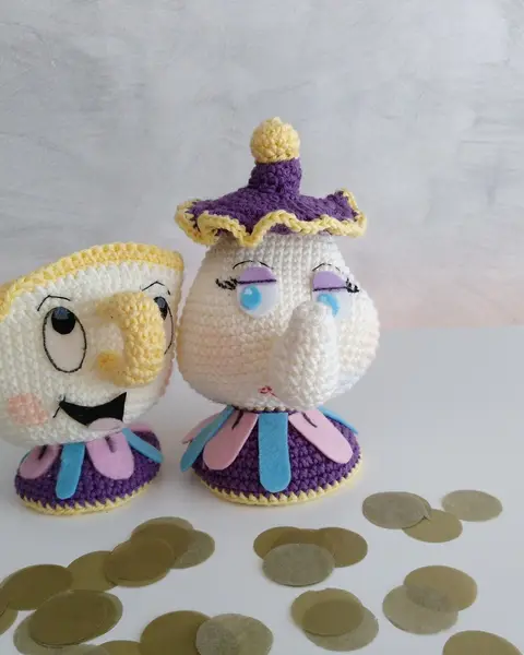 Amigurumis de una tetera blanca con tapa lila y una tacita con cara sonriente, tejidos a crochet