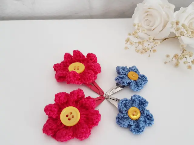 Dos clips de pelo con flores de crochet en rojo, amarillo y azul, con botones en el centro
