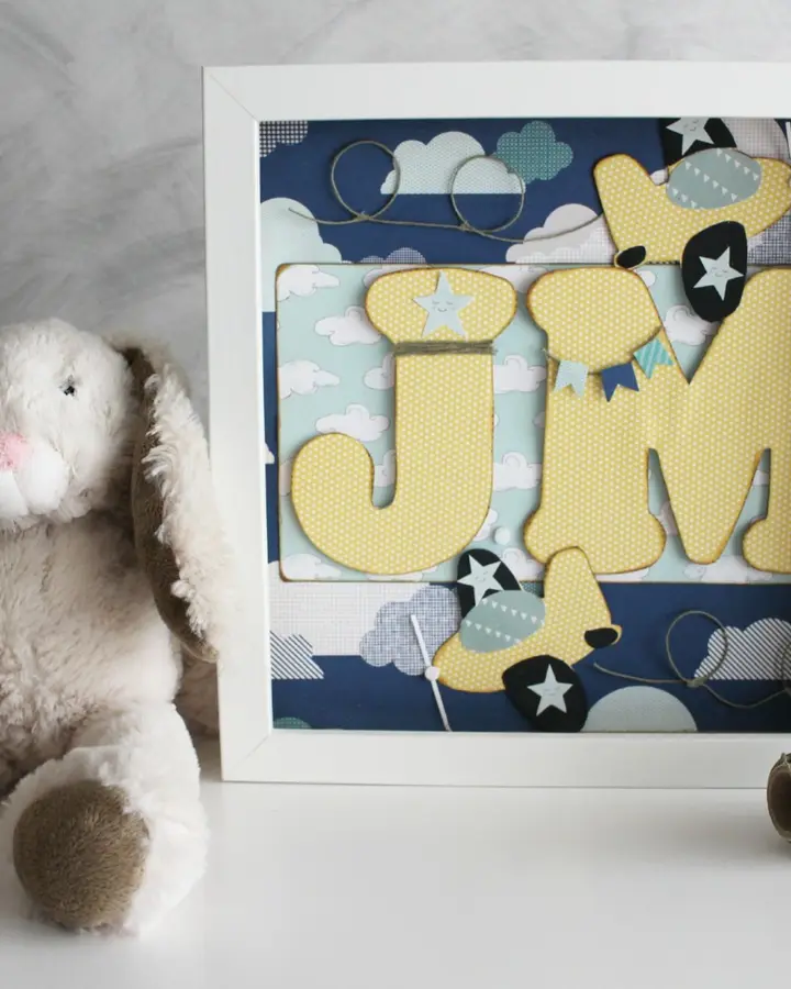 Cuadro infantil de papel con aviones y nombre en relieve, tonos azules y blancos