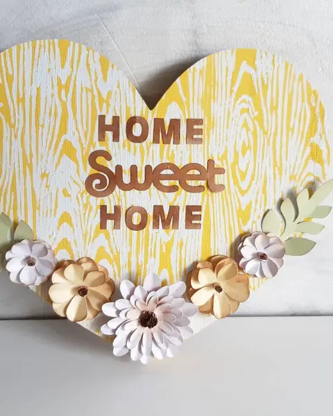 Corazón de madera pintado en amarillo con flores de papel y texto Home Sweet Home