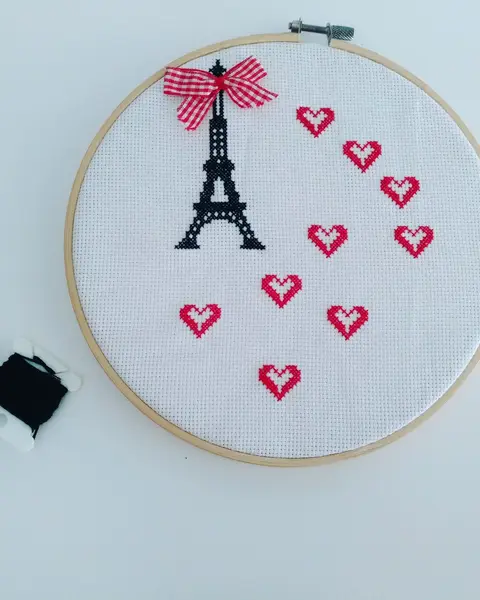 Bastidor de madera con la torre Eiffel bordada en punto de cruz y corazones alrededor