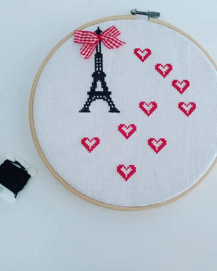 Bastidor de madera con la torre Eiffel bordada en punto de cruz y corazones alrededor