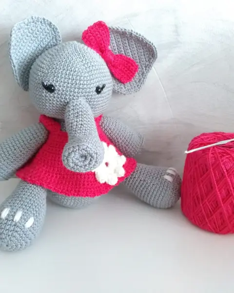 Elefanta amigurumi gris con vestido rojo de flores y lazo, tejida a crochet