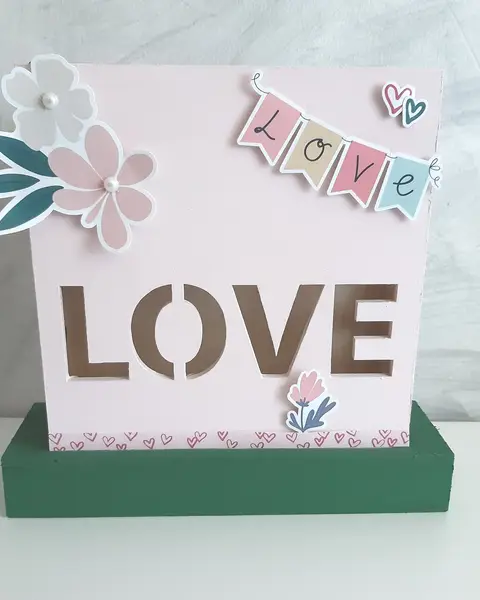 Lámpara de madera blanca con la palabra Love recortada y frente decorado con papel