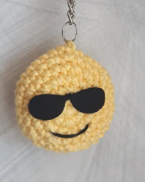 Llavero de crochet amarillo con forma de emoji sonriente con gafas de sol negras