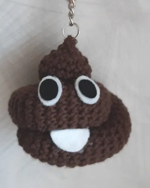 Llavero de crochet marrón con forma de emoji de caca sonriente con ojos blancos de fieltro