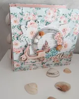 Maxi álbum de scrapbooking cerrado con tapa de flores coral y verde agua, ventana redonda y conchas