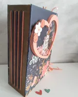 Mini álbum de boda visto de lado, con el lomo cosido a mano y papeles florales