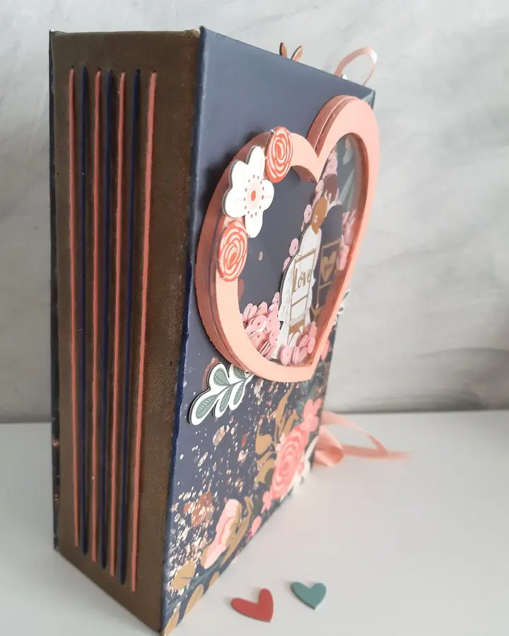 Mini álbum de boda visto de lado, con el lomo cosido a mano y papeles florales