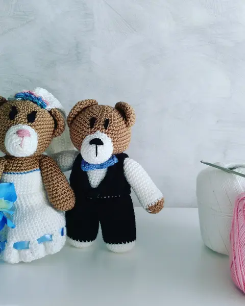 Pareja de osos amigurumi vestidos de novios: vestido blanco con ramo azul y traje negro con pajarita