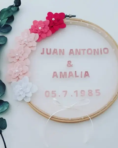 Porta alianzas en bastidor con tul rosa, guirnalda de flores de fieltro fucsia y blancas y eucalipto