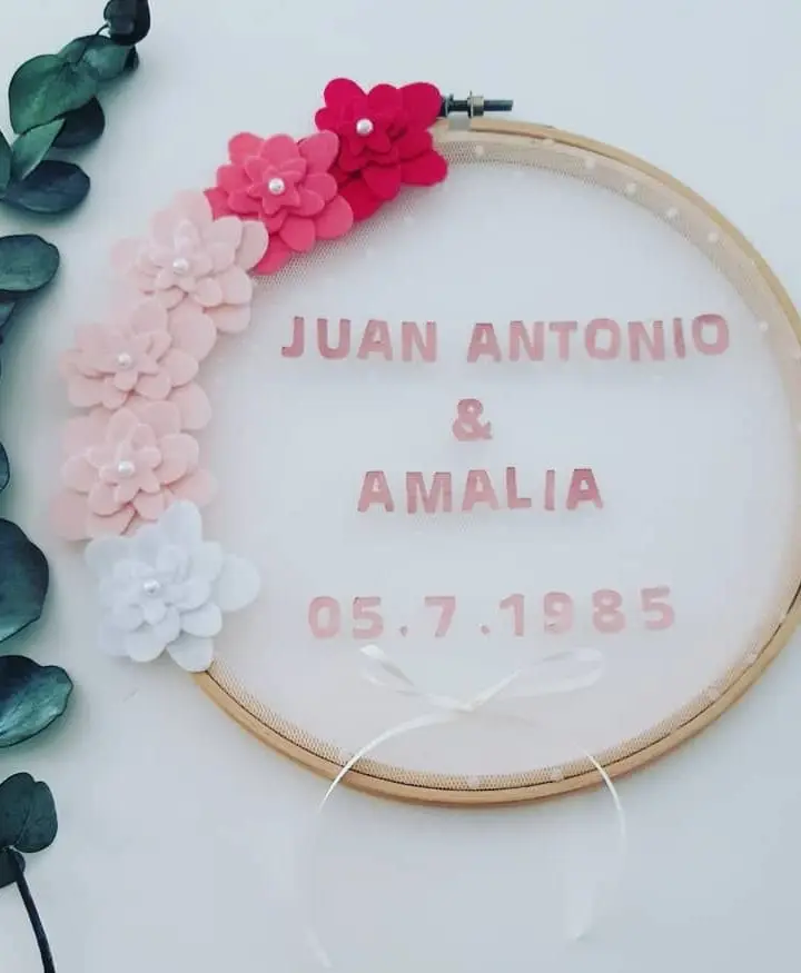 Porta alianzas en bastidor con tul rosa, guirnalda de flores de fieltro fucsia y blancas y eucalipto