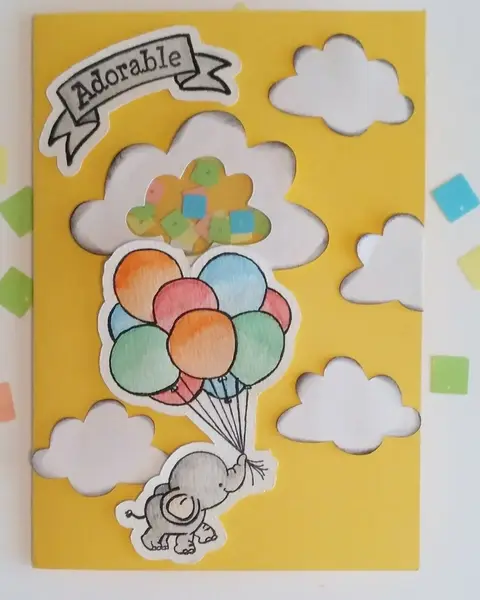 Postal de nacimiento amarilla con nubes blancas, elefante con globos de colores y letrero Adorable